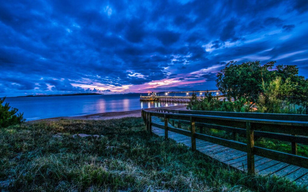 Passerelle en bois menant à une jetée illuminée au crépuscule, côte de Punta del Este, Uruguay