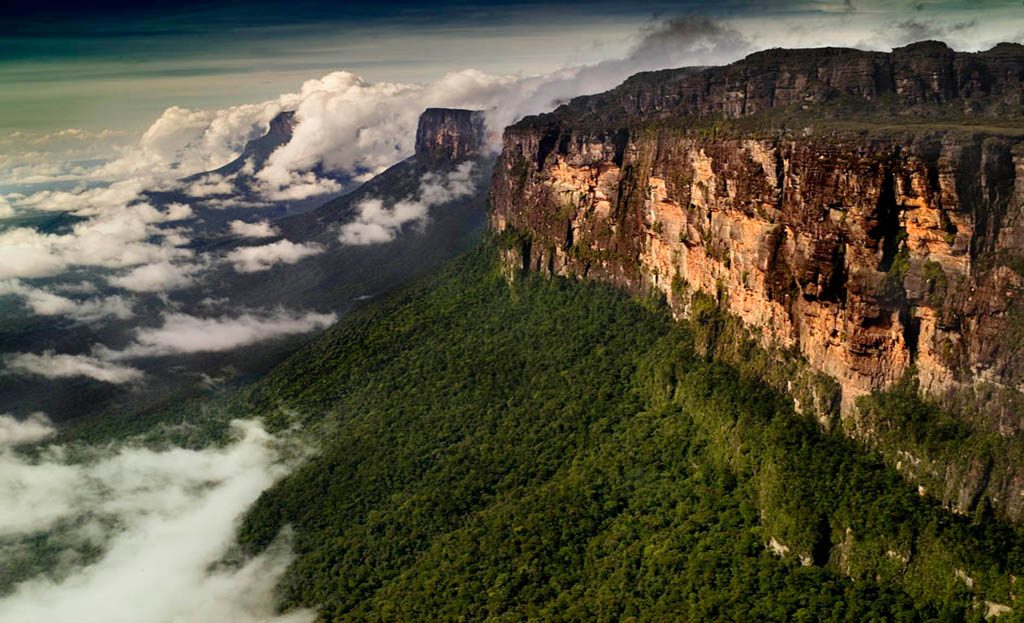 Falaises abruptes d'un tepui vénézuélien entouré de nuages et de forêt tropicale dense