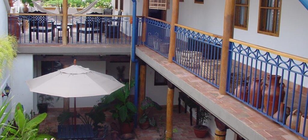 Patio intérieur d'une maison coloniale avec balcon bleu et grandes jarres en terre cuite, Venezuela