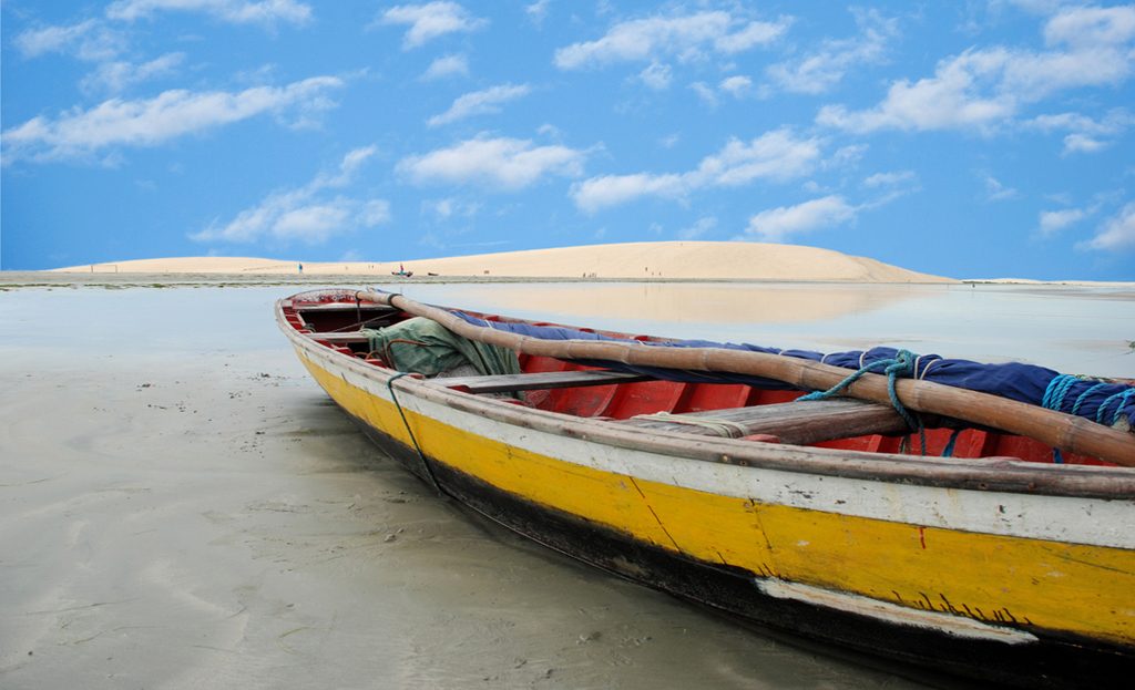 Bateau de pêche coloré échoué sur le sable près des dunes de Jericoacoara au Brésil