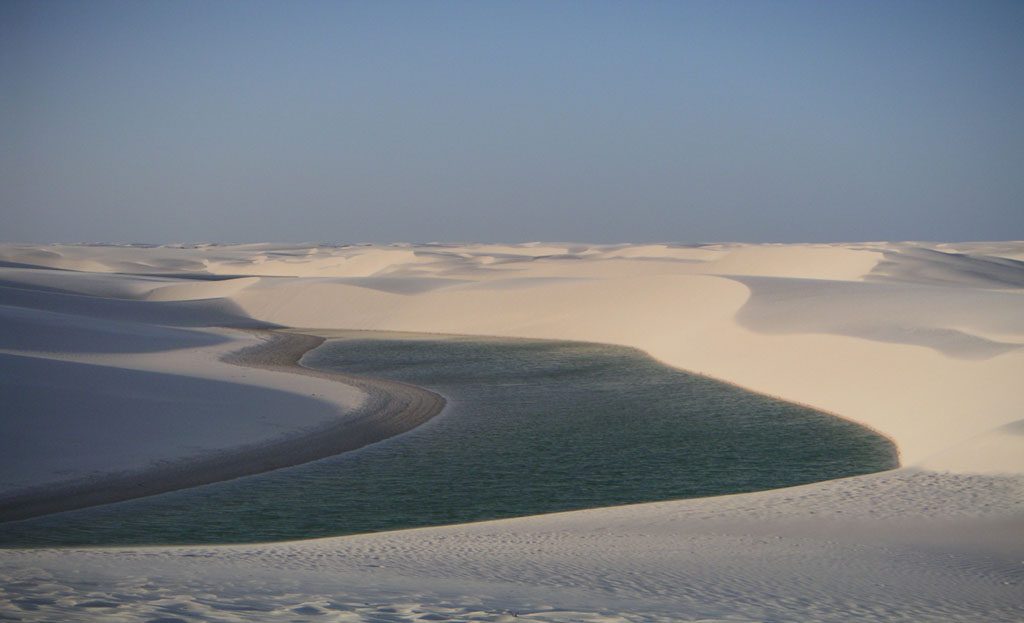 Lagune d'eau verte entourée de dunes de sable blanc à Lençóis Maranhenses, Brésil