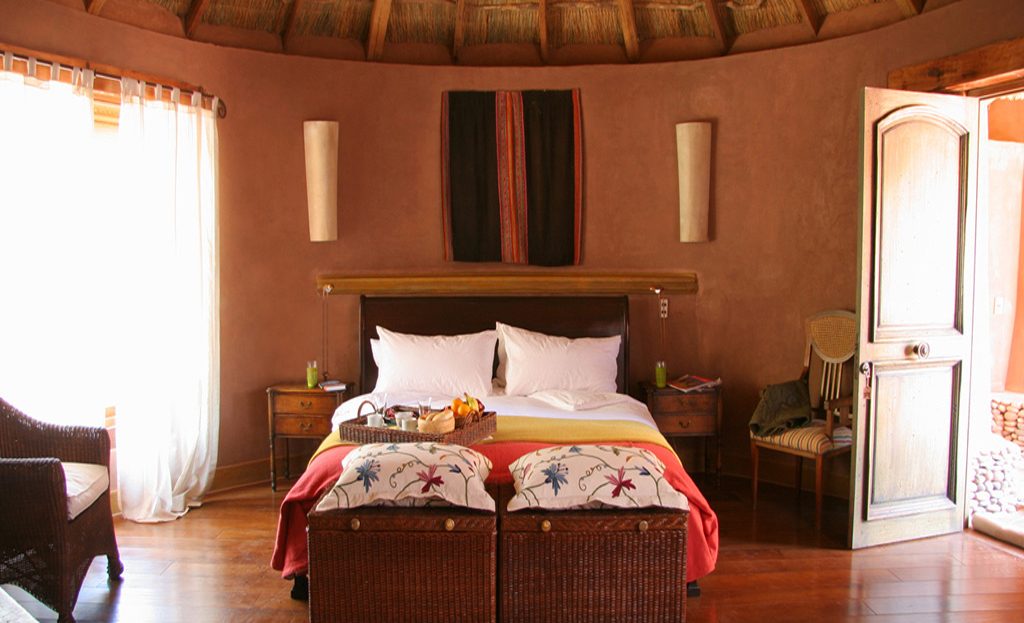 Chambre d'hôtel circulaire avec toit en chaume, lit double et décoration andine, San Pedro de Atacama