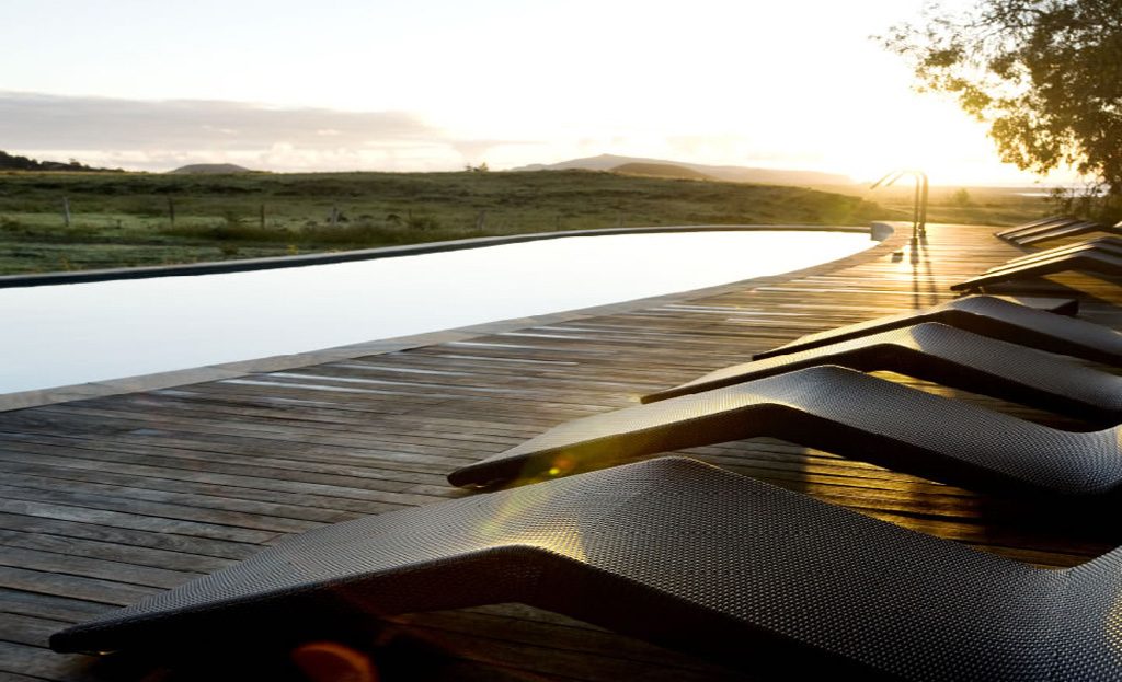 Piscine à débordement avec transats en bois au coucher du soleil, île de Pâques, Chili