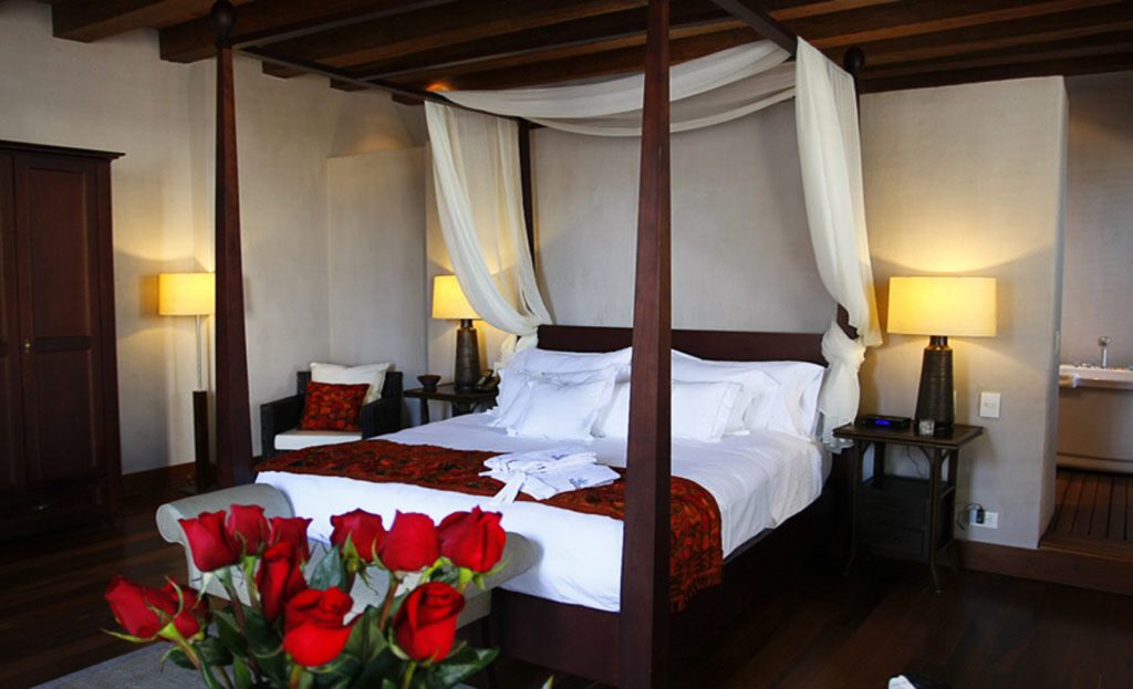 Chambre d'hôtel à Carthagène avec lit à baldaquin, roses rouges et lampes allumées