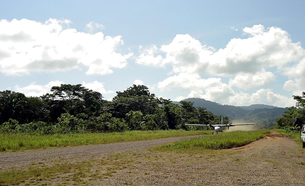 Petit avion taxi roulant sur une piste en terre bordée de forêt, péninsule d'Osa, Costa Rica