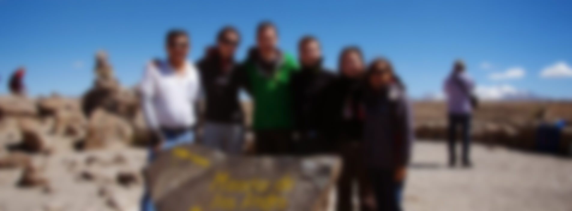 Groupe de voyageurs posant ensemble près d'un panneau en pierre sous un ciel bleu