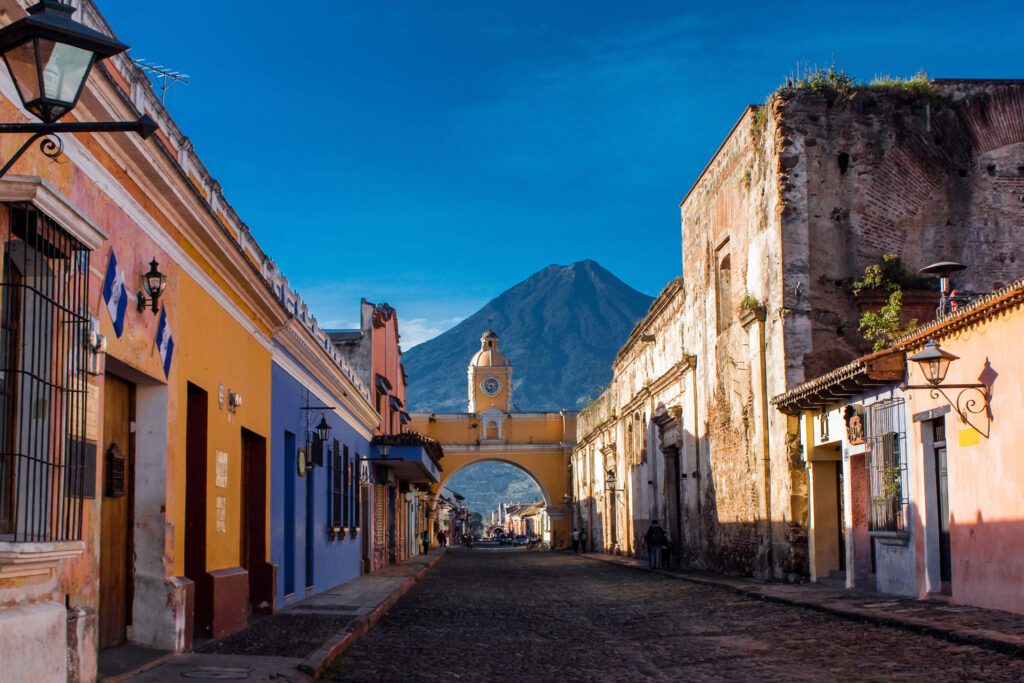 Arche de Santa Catalina et volcan derrière une rue pavée d'Antigua Guatemala