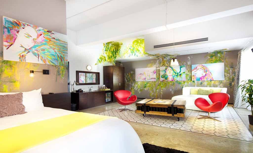 Chambre d'hôtel design à Panama City avec fauteuils rouges, canapé blanc et peintures murales colorées