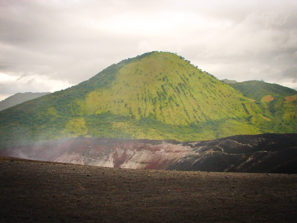 Vue du cratère volcanique noir avec fumerolles et colline verte en arrière-plan, Cerro Negro, Nicaragua