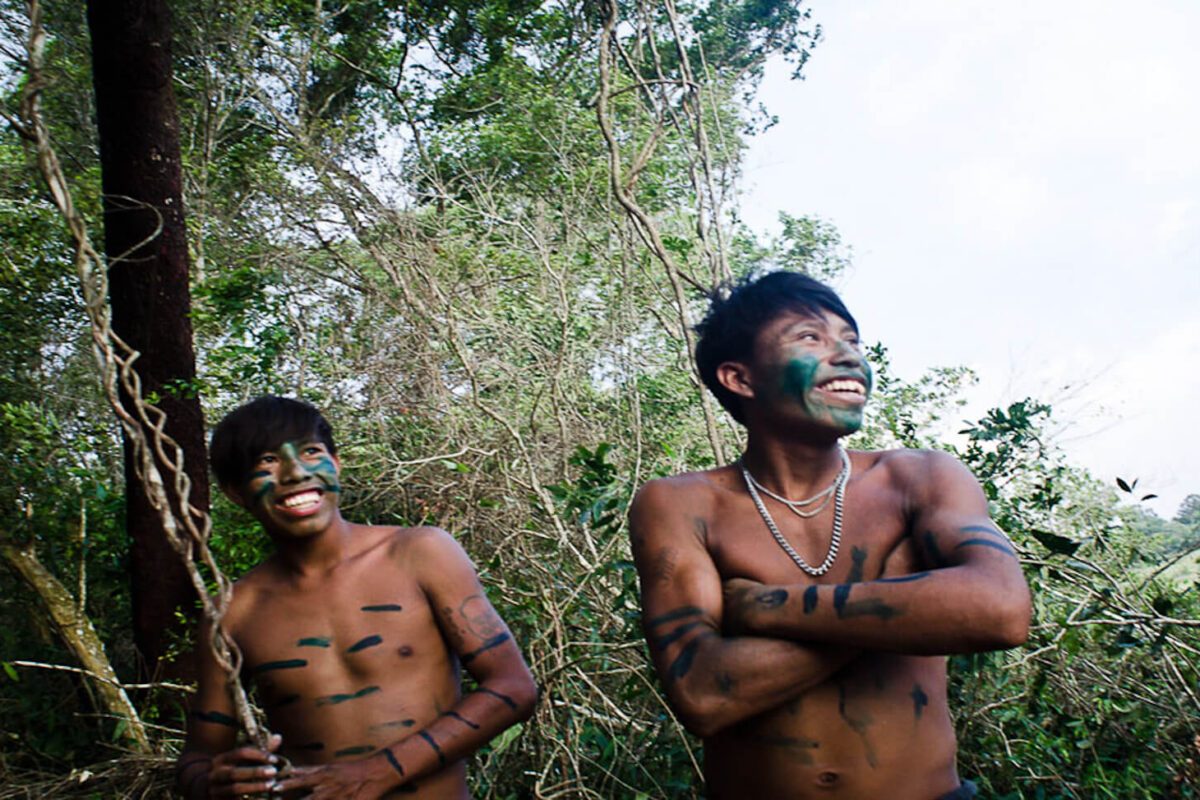 Deux hommes guaranis souriants avec peintures corporelles traditionnelles dans la forêt paraguayenne