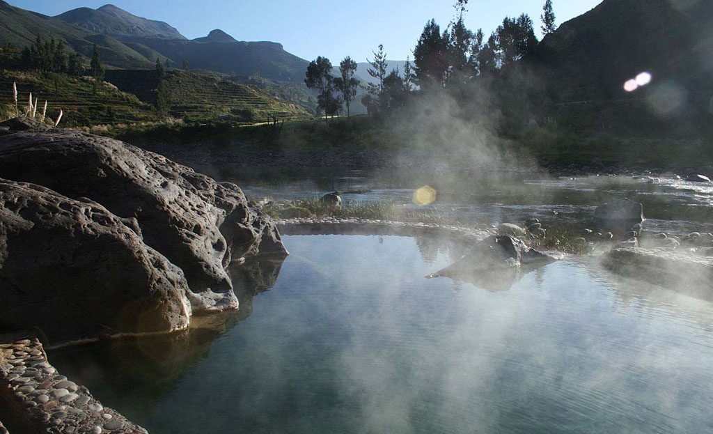 Piscine thermale fumante entourée de rochers, le matin dans le canyon de Colca, Pérou