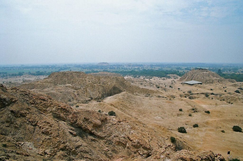 Site archéologique désertique avec pyramides érodées et bâtiment moderne, côte nord du Pérou