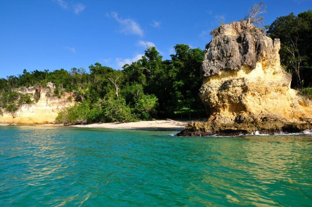 Falaise rocheuse et petite plage entourée de forêt tropicale à Cayo Saetia, Cuba