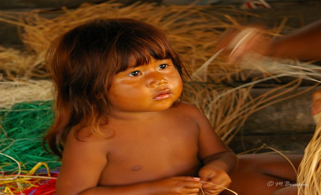 Enfant Warao assis près de fibres végétales pour tissage, Delta de l'Orénoque, Venezuela