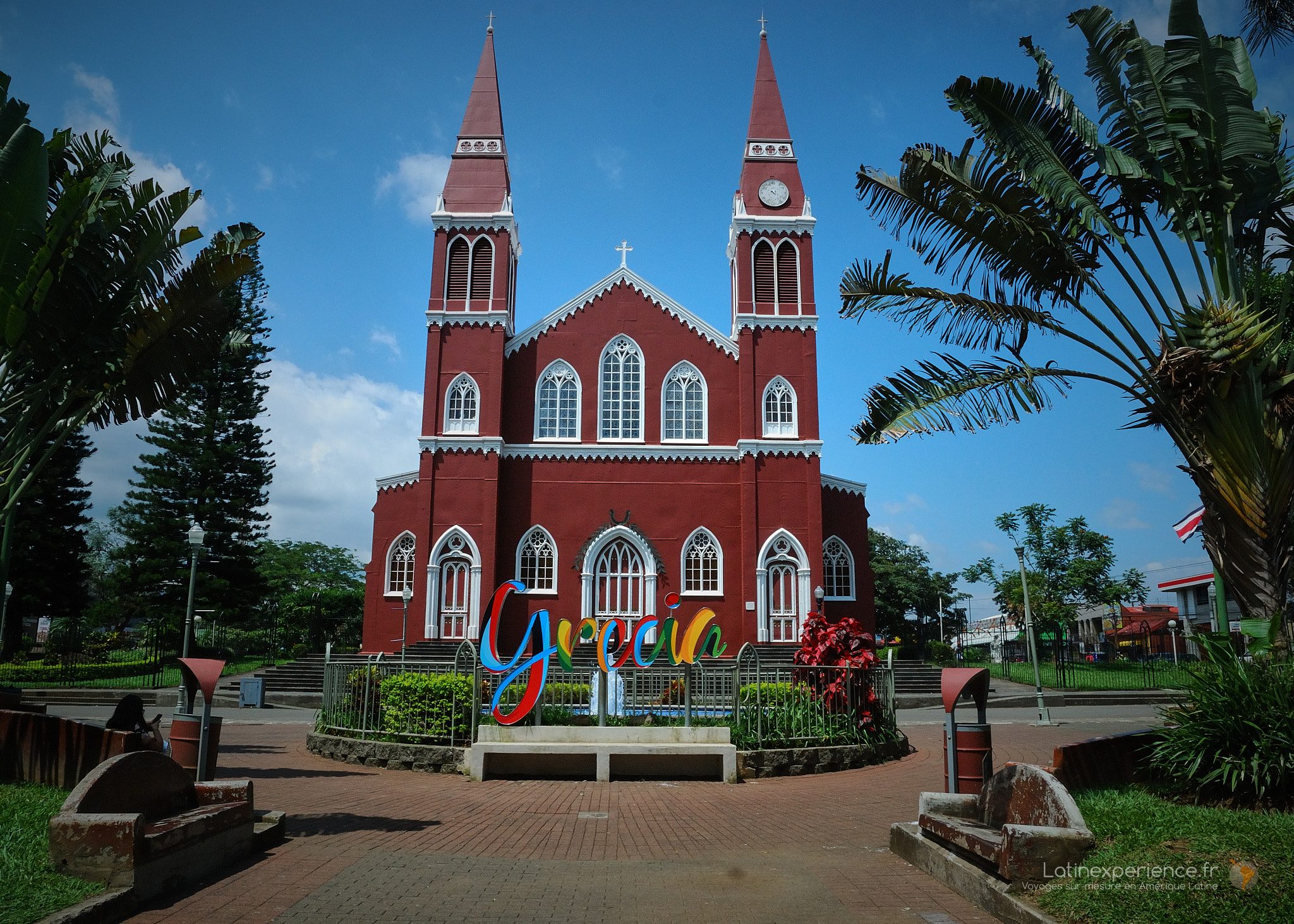 Église métallique rouge de Grecia au Costa Rica, place ornée de palmiers