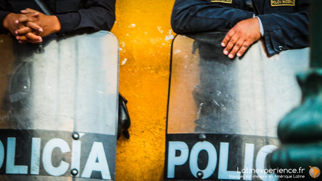 Deux policiers péruviens avec boucliers anti-émeute marqués Policia devant un mur ocre