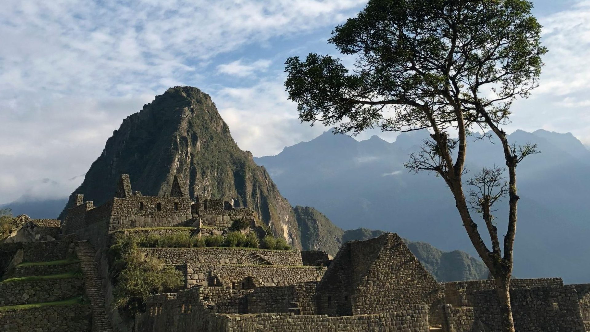 Ruines en pierre du Machu Picchu avec pic rocheux et montagnes andines en arrière-plan