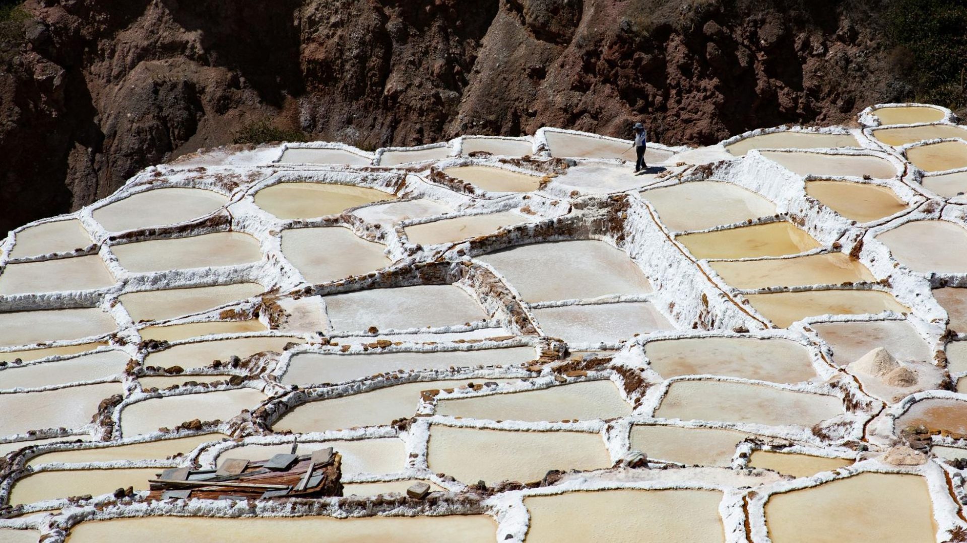 Salines de Maras avec bassins blancs en terrasses et une personne marchant au sommet